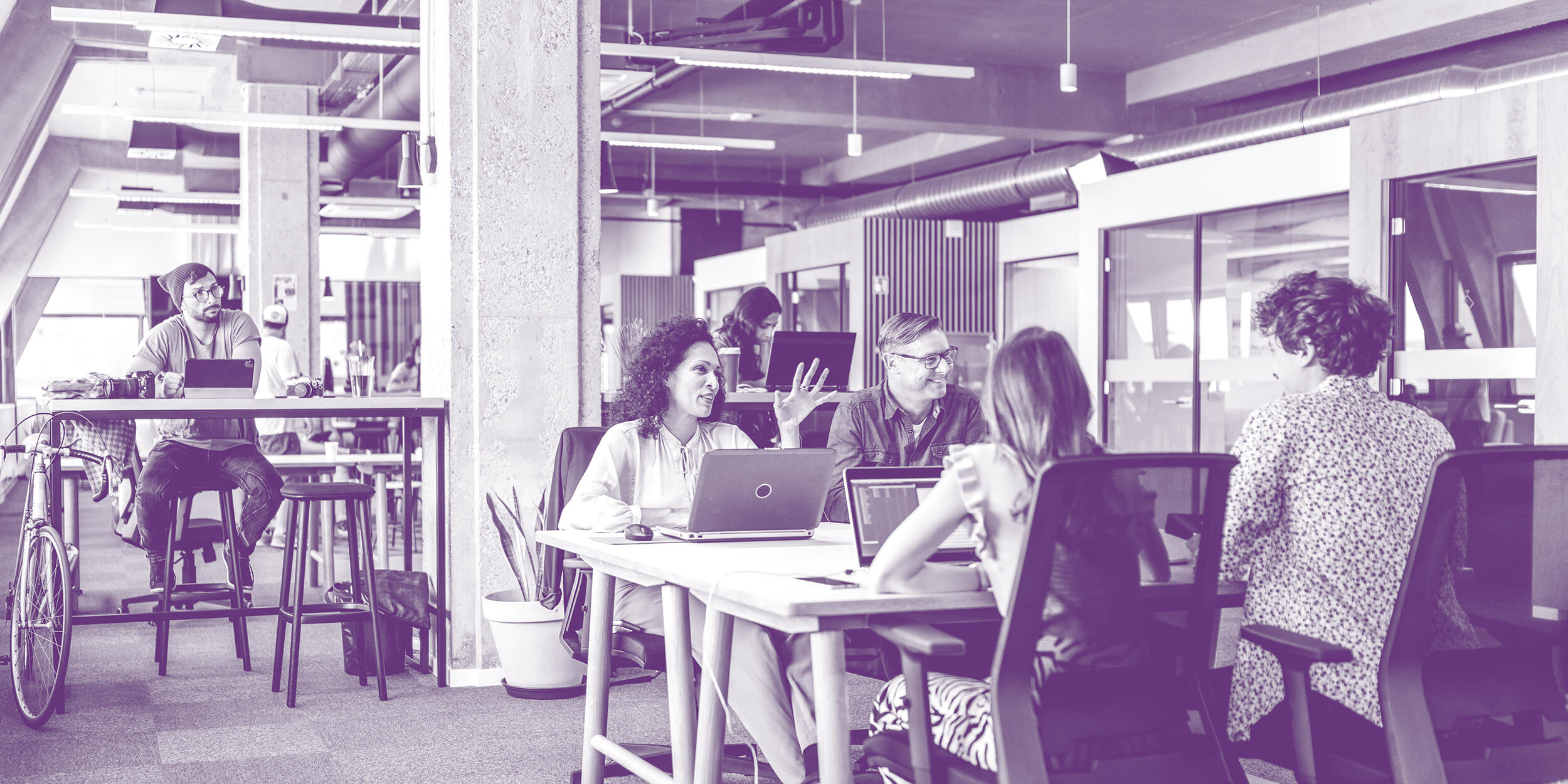 A team of people sitting at laptops smiling and engaging with one another